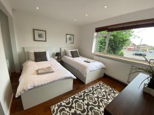 a bedroom with two beds and a window at Msquared Villa, Modern 3-Bedroom House, 3 Parking Spaces in Kidlington