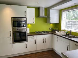 a kitchen with white cabinets and a stove top oven at Msquared Villa, Modern 3-Bedroom House, 3 Parking Spaces in Kidlington