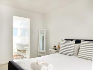 a white bedroom with a large bed and a bathroom at Palace Hill Apartment in Cape Town