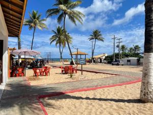 - une plage avec des tables, des chaises et des palmiers dans l'établissement Baixio - Residencial Ponta de Inhambupe, à Baixio