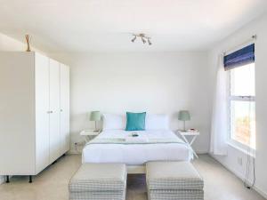 a white bedroom with a large bed and two chairs at Palace Hill Apartment in Cape Town