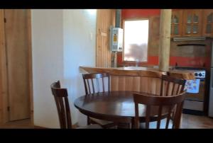 - une cuisine avec une table et des chaises en bois ainsi qu'un comptoir dans l'établissement cabaña rustica LEMU isla negra, à Isla Negra