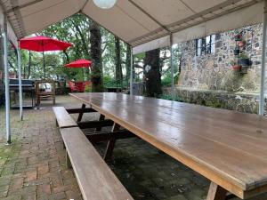 drewniany stół piknikowy z dwoma czerwonymi parasolami w obiekcie Hermosa cabaña en el bosque w mieście Tres Marías