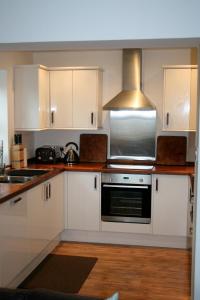 a kitchen with white cabinets and a stove top oven at Quinag - luxury villa with sea views in Achiltibuie in Achiltibuie