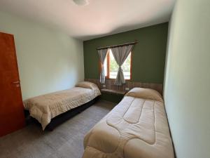 two beds in a room with green walls and a window at Cabañas Amanecer de Montaña in Malargüe