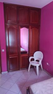a bedroom with a white chair and a pink wall at Casa de Gá in Mindelo