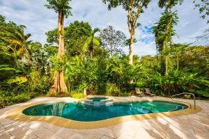 einen Pool inmitten eines Gartens mit Bäumen in der Unterkunft El Nido Jungle Lodge in Puerto Viejo