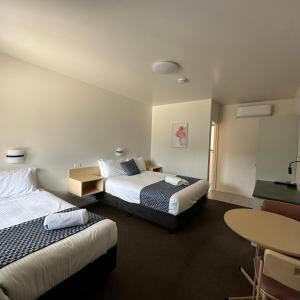 um quarto de hotel com duas camas e uma mesa em SHEPPARTON MOTOR INN Tudor House Motel em Shepparton