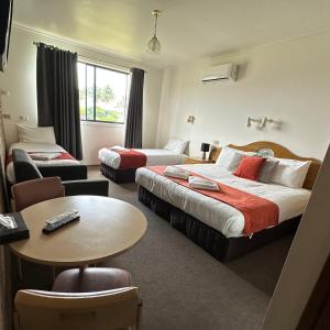 a hotel room with two beds and a table at SHEPPARTON MOTOR INN Tudor House Motel in Shepparton