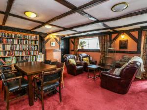 a library with chairs and a table and bookshelves at The House at Bridge of Lochay in Killin