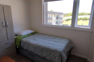 niewielka sypialnia z łóżkiem i oknem w obiekcie Comfortable and quiet apartment. Pelluco Alto w mieście Puerto Montt