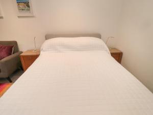 Cama blanca en habitación con sofá en Silverbirch en Cornhill-on-tweed