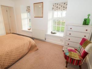 1 dormitorio con 1 cama, vestidor y silla en Bakers Cottage, en Cornhill-on-tweed
