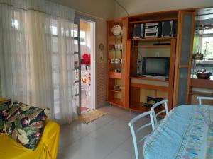 sala de estar con sofá amarillo y TV en Casa Completa no Rosa, en Praia do Rosa