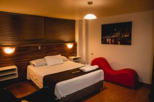 um quarto de hotel com uma cama e uma cadeira vermelha em HOTEL SAN FRANCISCO - Moquegua em Moquegua