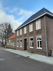 - un bâtiment en briques dans une rue avec une église dans l'établissement Herberg Lambic, à Blitterswijck