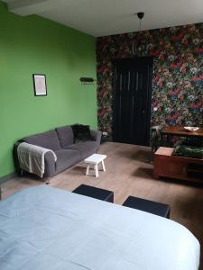 een woonkamer met een bank en een groene muur bij Herberg Lambic in Blitterswijck