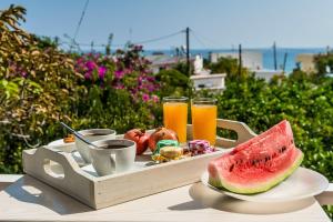 a tray of drinks and a plate of watermelon and juice at Alpha Stegna Sun in Archangelos