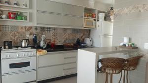 a kitchen with white cabinets and a white stove at AMPLA COBERTURA NA PRAIA DO MAR GROSSO LAGUNA in Laguna