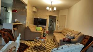 a living room with two couches and a tv at AMPLA COBERTURA NA PRAIA DO MAR GROSSO LAGUNA in Laguna +21 photos