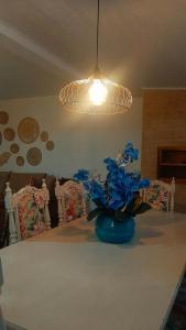 Una mesa con un jarrón azul con flores azules. en AMPLA COBERTURA NA PRAIA DO MAR GROSSO LAGUNA, en Laguna