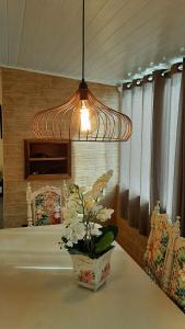 a light hanging over a table with a vase of flowers at AMPLA COBERTURA NA PRAIA DO MAR GROSSO LAGUNA in Laguna
