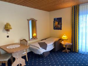 ein Hotelzimmer mit einem Bett, einem Tisch und einem Schreibtisch in der Unterkunft Hotel Forellenhof in Pottenstein