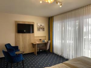 a hotel room with a bed and a desk and a television at Hotel Forellenhof in Pottenstein