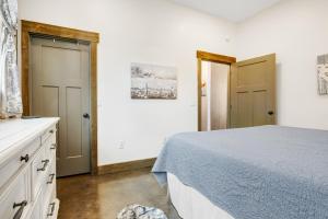 a white bedroom with a bed and two doors at West Side Nest in Fredericksburg