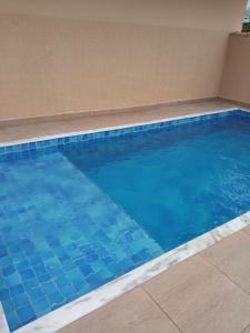 - une grande piscine revêtue de carrelage bleu dans l'établissement Apartamento aconchegante em frente à praia., à Ubatuba