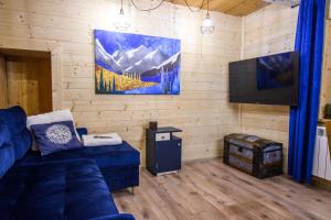 uma sala de estar com um sofá azul e uma televisão de ecrã plano em Apartament Stryszek Alpinistyczny em Bukowina Tatrzańska