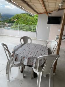 a table and chairs on a balcony with a table and a television at Casa com Praia no quintal in Angra dos Reis