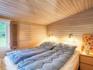 a large bed in a room with a wooden wall at Holiday home Hornbæk IX in Hornbæk