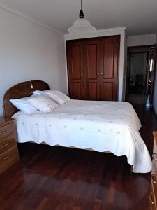 Schlafzimmer mit einem großen Bett mit einem Kopfteil aus Holz in der Unterkunft Apartamento Mar e Sol in Gafanha da Nazaré