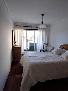 a white bedroom with a bed and a window at Apartamento Mar e Sol in Gafanha da Nazaré