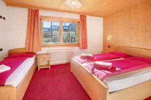 Duas camas num quarto com tapete vermelho em Appartamenti Bait da Erich em Livigno