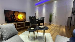 D&D Schönbrunner Deluxe Apartment في فيينا: غرفة معيشة مع طاولة وكراسي وتلفزيون