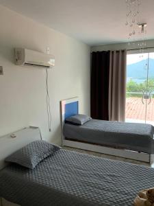 a bedroom with two beds and a window with a view at Casa com Praia no quintal in Angra dos Reis
