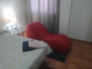 a red chair sitting in a room next to a bed at Paraiso Huertano in Alquerías