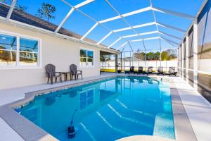 a swimming pool with a pergola and chairs in a house at Potomac Escape - Unit B in Palm Coast