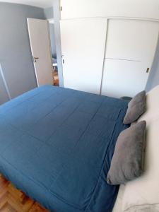 a bedroom with a blue bed with pillows on it at Apartamento Nueva Córdoba in Cordoba