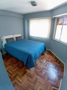 a bedroom with a blue bed and a wooden floor at Apartamento Nueva Córdoba in Cordoba