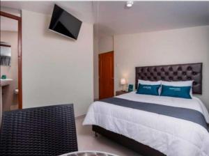 a bedroom with a bed with blue pillows and a television at Hotel Luna de Oro Cusco in Cusco