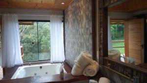 uma casa de banho com uma banheira e um espelho grande em Pousada Trinca Ferro em Bom Retiro