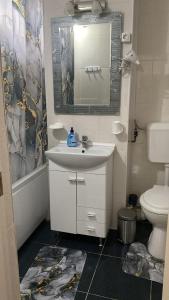 a bathroom with a sink and a toilet and a mirror at Elite Apartment in Târgovişte