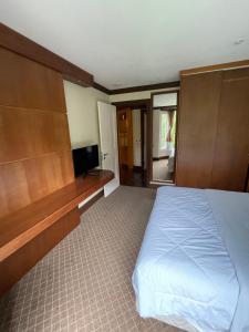 1 dormitorio con 1 cama y TV de pantalla plana en Privilege Apart hotel Mountain Village, en Canela