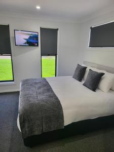 um quarto com uma cama grande e 2 janelas em CH Boutique Apartments The Ringers Road em Tamworth