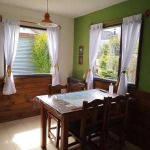 a dining room with a table and two windows at Cabañas Paso de Viento in El Chalten