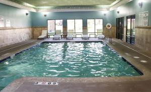 ein Swimmingpool mit Stühlen in einem Gebäude in der Unterkunft Holiday Inn Express Cedar Rapids - Collins Road by IHG in Cedar Rapids