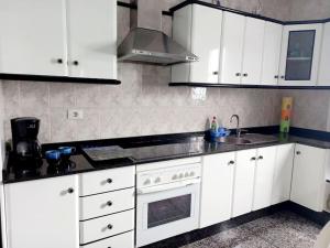 a kitchen with white cabinets and a sink and a stove at Casa Caleta Caballo in Caleta de Caballo